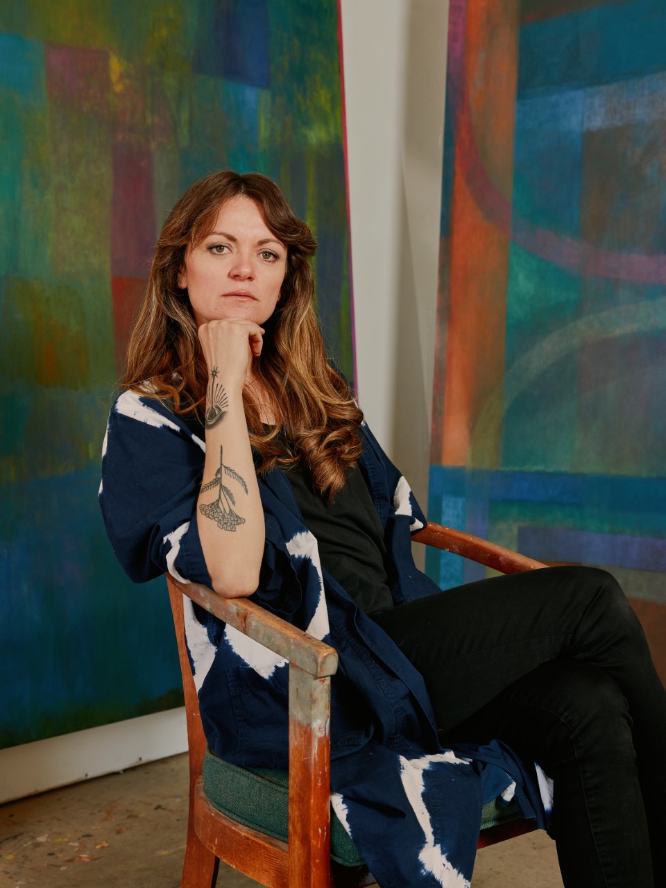 Maja Ruznic seated in chair in front of large artworks